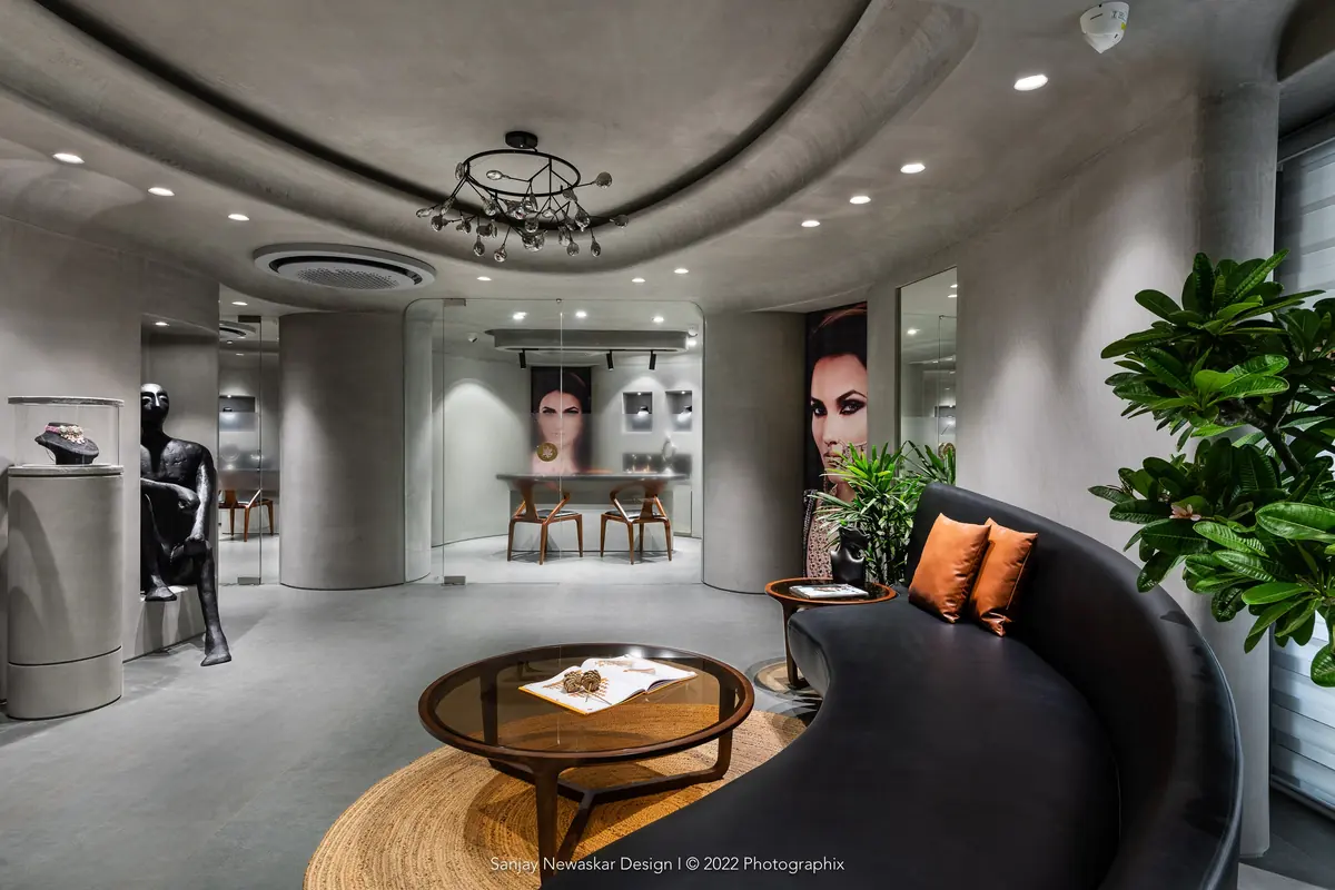 Organic Forms jewellery studio: curved grey walls, sculptural display plinths and a curving dark sofa around a round table.